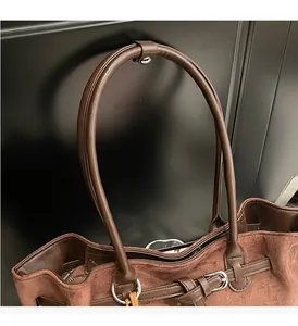 Detail of sturdy brown faux suede tote handles with silver metal rings and stitching