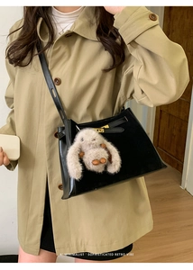 Detail view of black retro bucket bag with metal lock and cute beige bunny charm