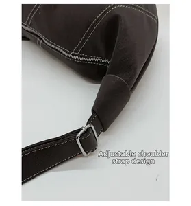 Détail macro de la bandoulière réglable avec boucle en métal argenté sur sac en cuir