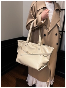 Dettaglio della borsa tote crema con trama in pelle e fibbia dorata in primo piano