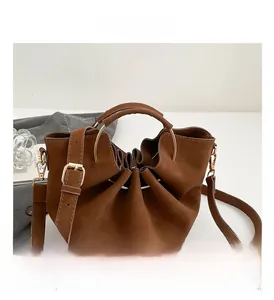 Detail view of brown pleated bucket bag with golden metal ring and leather handles