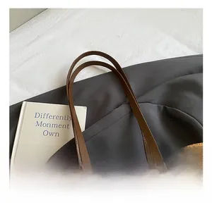 Détail du sac cabas en daim avec bandoulière en cuir, boucle métal et ours peluche