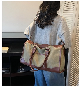 Détail du sac de voyage en toile vert armée avec poignées en cuir marron porté par un mannequin