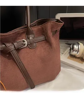 Detail view of brown suede tote bag with leather strap, silver buckle and soft texture
