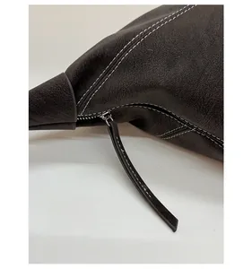 Détail du zip argenté et surpiqûres blanches contrastées sur sac en cuir marron foncé