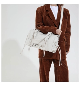 Détail d'un sac à main en cuir blanc texturé avec de longues franges et métal argenté