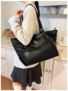 Dettaglio di una borsa tote grande in pelle nera a grana con eleganti accessori dorati