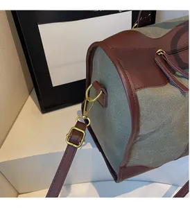 Close-up of golden hardware and leather trim on an olive green canvas tote bag