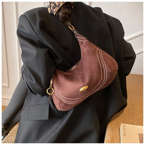 Detail of brown suede crescent bag with contrasting white stitching and gold hardware