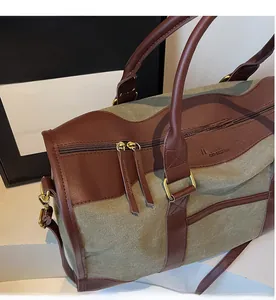 Detail of canvas tote with leather trim, dual zippers, and adjustable shoulder strap