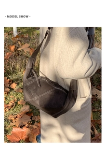 Détail du sac dumpling en daim marron foncé avec surpiqûres sur manteau beige