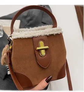 Detail of suede bucket bag with gold clasp, fleece trim and small bear charm