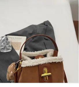 Detail of brown suede bucket bag featuring white faux fur trim and gold twist lock