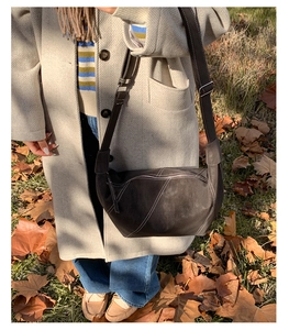 Detail of dark brown crescent bag featuring white contrast stitching and adjustable strap