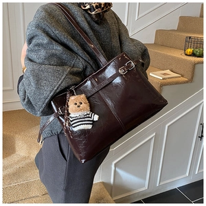 Détail d'un sac cabas marron foncé avec texture en cuir froissé et charm ours mignon