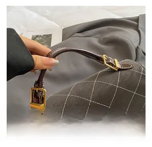 Detailed macro view of the textured quilting and golden swivel lock on a grey handbag