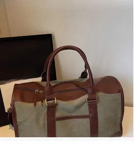 Close-up of olive green canvas travel bag featuring brown leather handles and metal hardware
