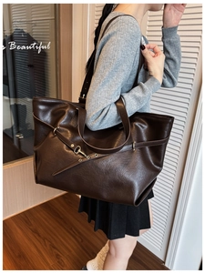 Dettaglio della borsa tote marrone scuro con fibbie metalliche e trama in pelle opaca sulla spalla