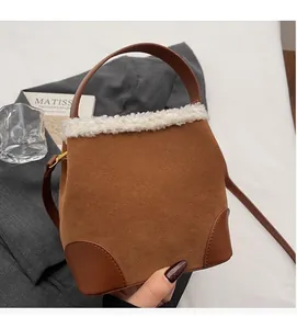 Detail of brown faux suede bucket bag with white faux fur trim and leather reinforcement