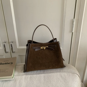 Detail of dark brown bucket bag featuring matte suede and smooth leather with gold lock