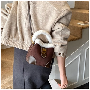 Détail d'un sac seau vintage en daim marron avec bordure en fourrure et fermoir doré