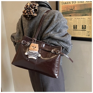 Dettaglio della borsa tote marrone scuro lucido con ciondolo a forma di orsetto e cinturini