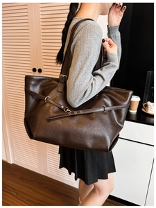 Dettaglio borsa tote marrone in pelle con trama litchi e cinturino con fibbia fine