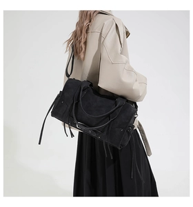 Black vintage tote bag with tassels and studs shown on a model for scale and style