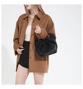 Close-up of brown suede oversized shirt jacket with a minimalist bucket bag on a model