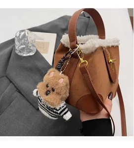 Detail of brown suede bucket bag with shearling trim and cute teddy bear charm