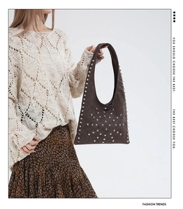 Detail of vintage dark brown suede shoulder bag with silver rivet studs on model