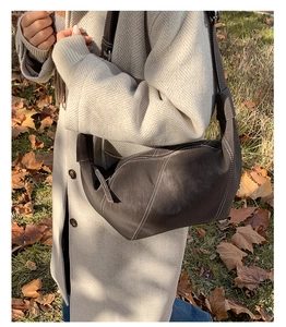 Close-up of dark brown crescent bag with distinct white contrast stitching details