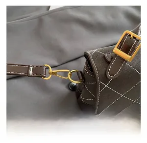 Detail of brown quilted faux leather bag with contrast stitching and gold metal hook