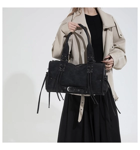 Détail d'un sac à main rétro noir avec boucle en métal, cordes tressées et franges