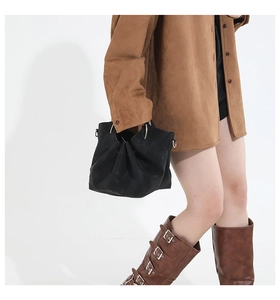 Detail of black pleated shoulder bag with metal ring handle on model with retro outfit