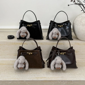 Detail view of stylish retro bucket bags in mixed leather finishes with cute rabbit charms