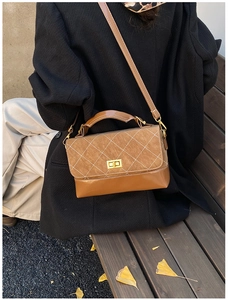 Detail of a brown quilted crossbody bag featuring a suede flap and golden metal clasp