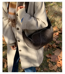 Detail of deep brown crescent bag with white contrast stitching and soft leather texture