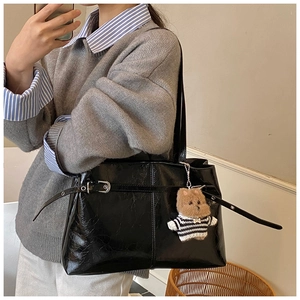 Détail du sac cabas noir brillant avec boucle métallique et charm ours en peluche