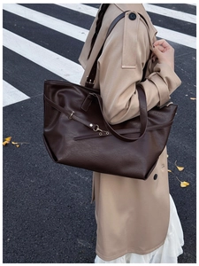 Scatto all'aperto di una modella con la grande borsa tote in pelle marrone scuro in città
