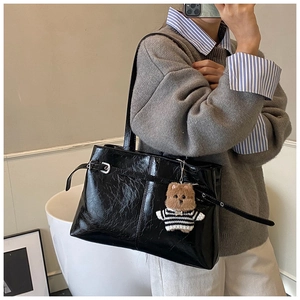 Détail du cabas en cuir verni noir brillant avec un joli petit ours en peluche sur le côté