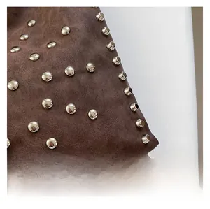 Macro shot of brown vintage distressed leather bag with polished silver round rivets