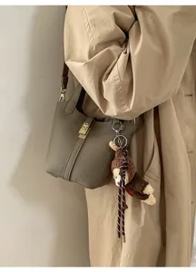 Détail du sac seau en cuir grainé avec fermoir doré et accessoire pendentif ours