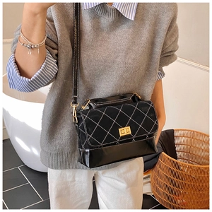 Detail of crossbody bag with quilted suede texture, gold twist lock, and metal chain strap