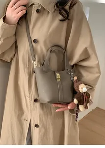 Détail du sac seau en cuir grainé gris avec fermoir doré et pendentif d'ours mignon