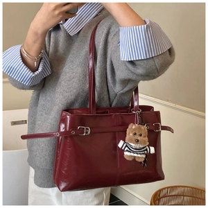 Détail du cabas en cuir bordeaux avec boucles métalliques et charmant porte-clés chien