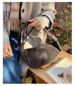 Detail of grey dumpling bag showing soft pleated leather and contrast white stitching