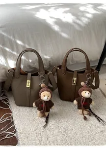 Détail de sacs seaux en similicuir taupe et marron avec breloques d'ours en peluche