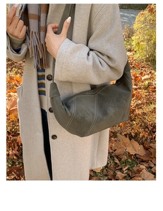 Detail of grey-green crescent bag featuring white contrast stitching on matte leather surface