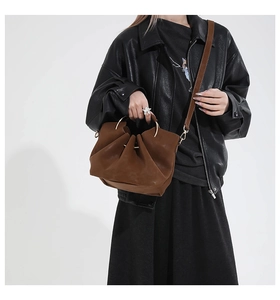 Braune Falten-Eimertasche mit goldenem Metallgriff und Schultergurt am Model
